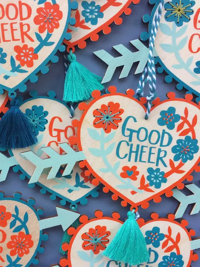 A collection of 'good cheer' charms are laid out, showing the colours and hand stitched detail