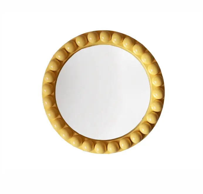 Round oversized bobbin mirror with a decorative bobbin-style wooden frame, hanging on a white wall.