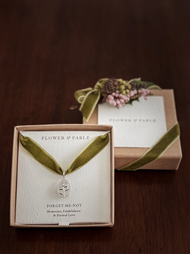 Sterling Silver Forget me not medal charm packaged on a green ribbon and gift box with flower posy