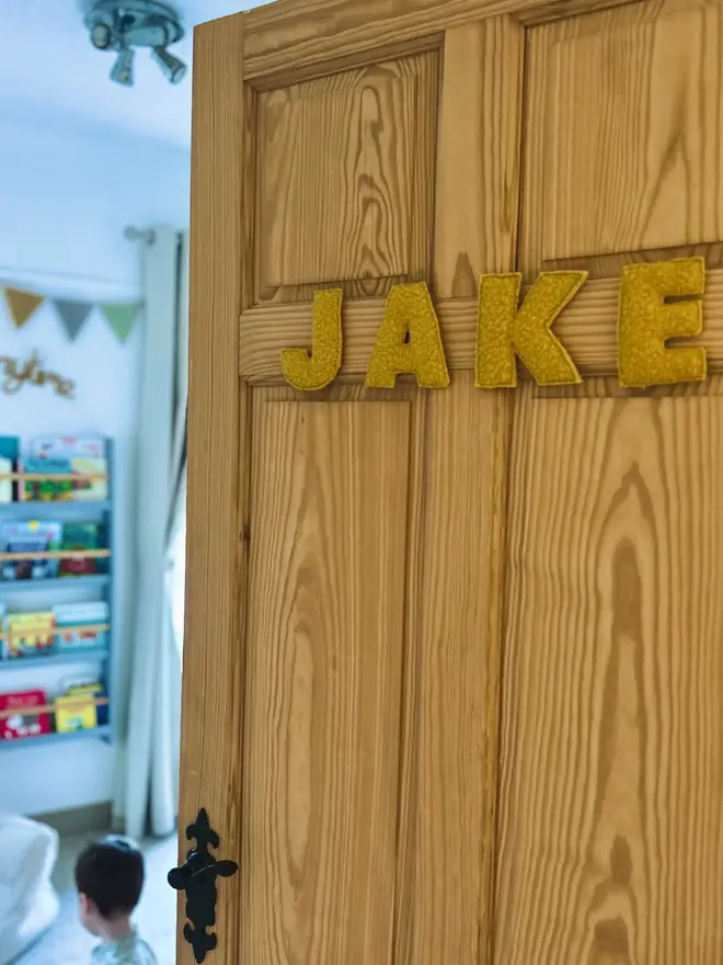 boucle letter bunting. yellow fabric bunting hung on a door spelling 'jake'.