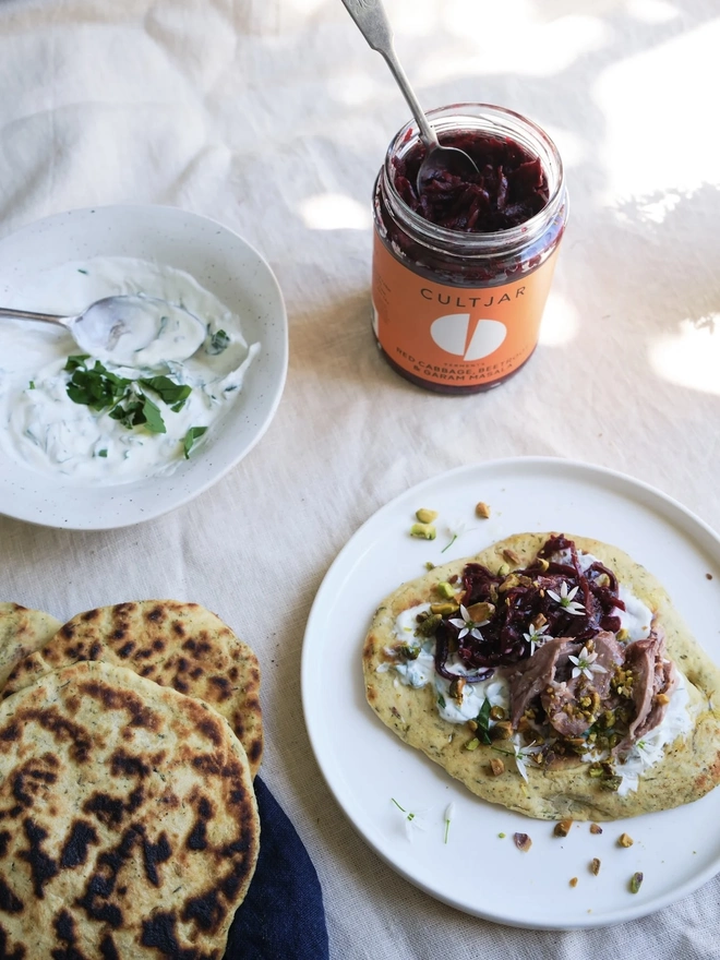 Ferment Intro Journey (Set Of 5), a jar of ferment sitting on a dining table. It is accompanied by other foods and drinks on a white surface. 