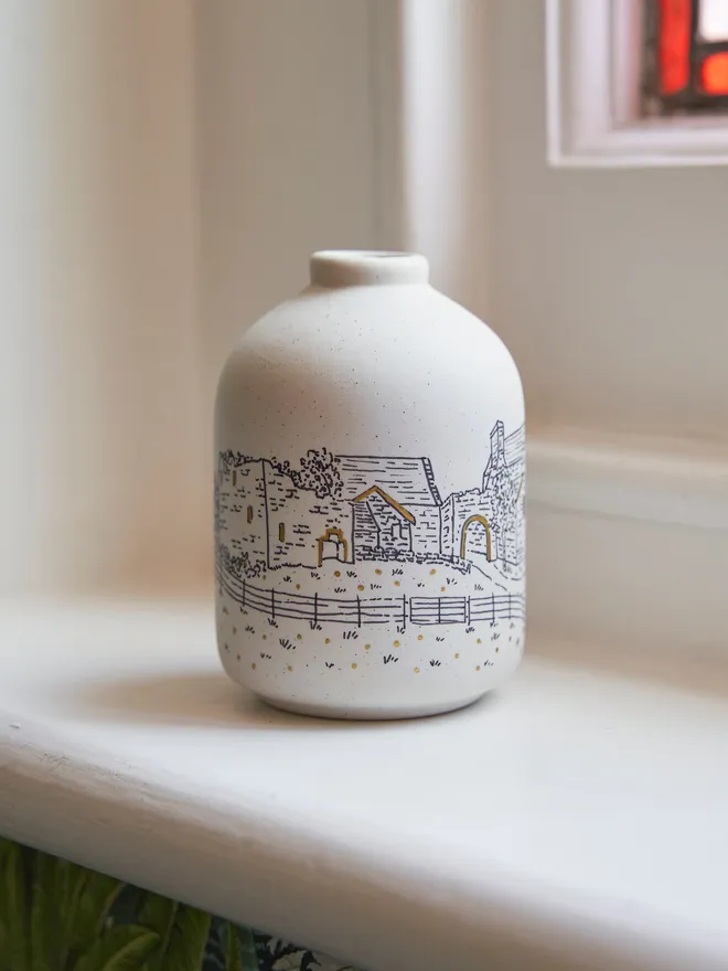 A ceramic vase featuring a black line drawing of a wedding venue
