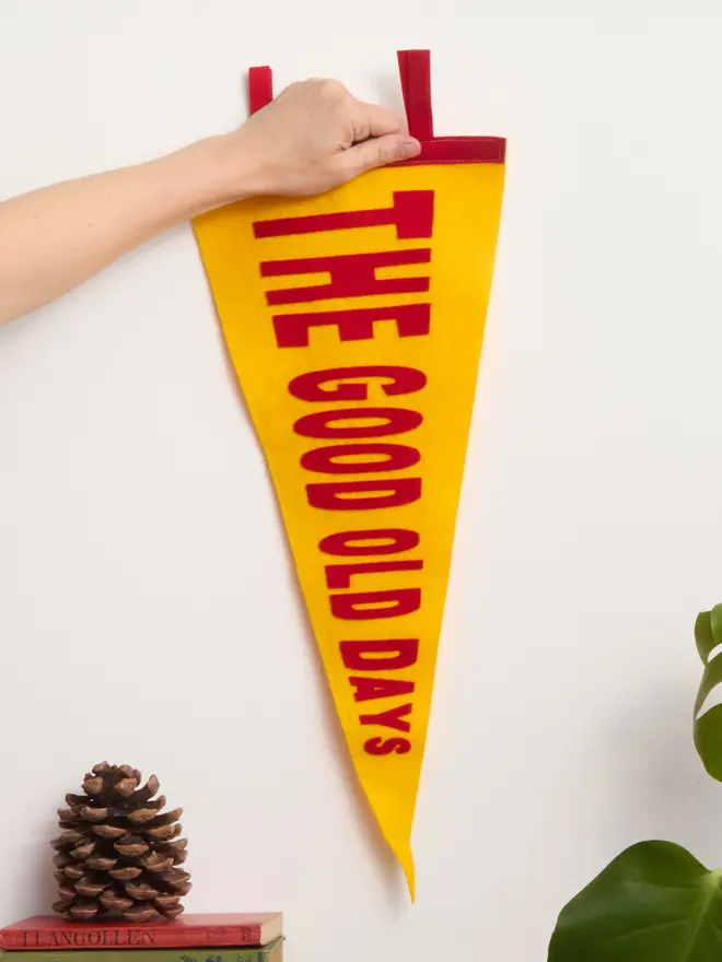 A yellow and red 'The good old days' pennant being held up by a hand