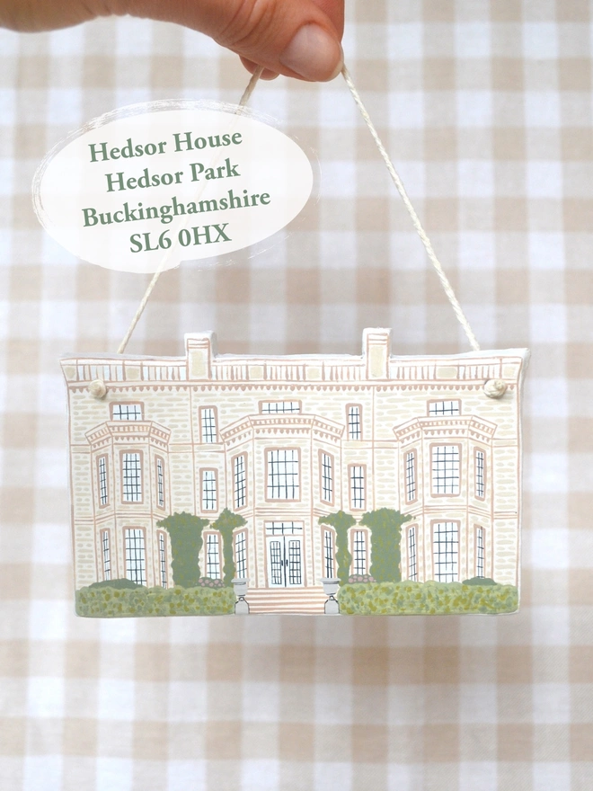 clay hanging design in the shape of a white wedding venue with gingham background