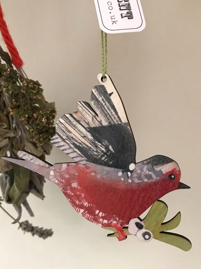 An illustrated Robin decoration hangs in front of a bunch of dry herbs