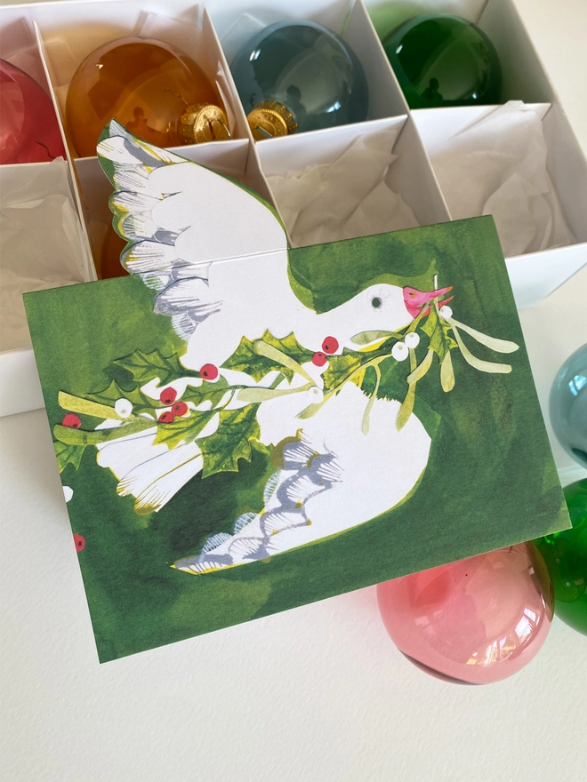 Esther Kent illustrated Christmas Card showing white goose on green inky background, carrying holly and mistletoe