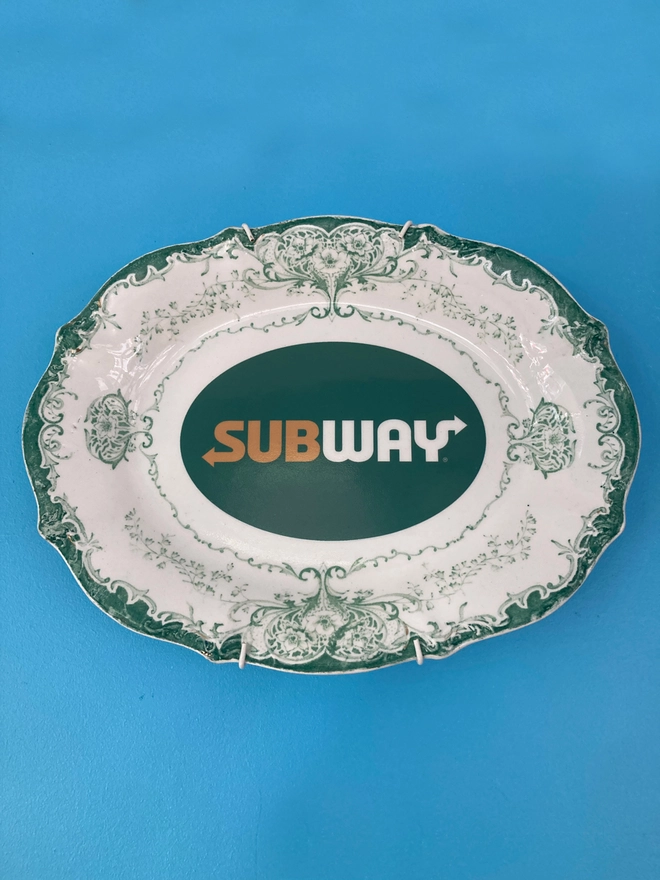 Vintage decorative green and white china plate with Subway logo in the middle.  