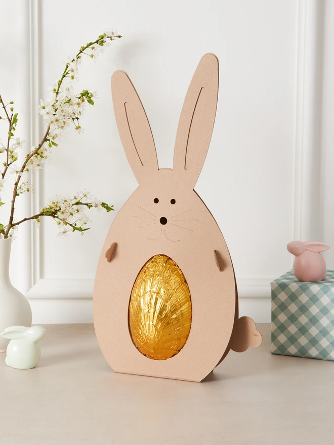 salted caramel milk chocolate easter egg. a chocolate egg photographed in gold foil within a cardboard rabbit.
