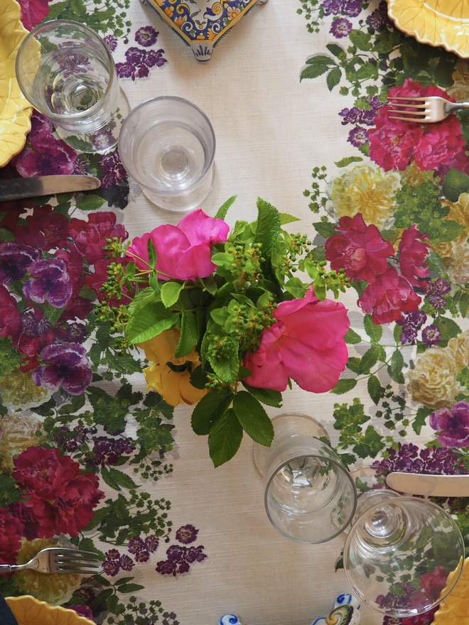 Hand painted roses printed onto a summer linen tablecloth decorated with vases of summer blooms