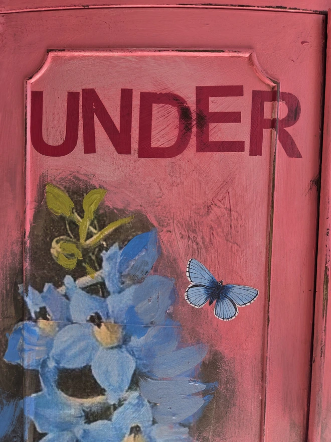 Close up of painted vintage wooden cabinet with pink, blue and floral decoration