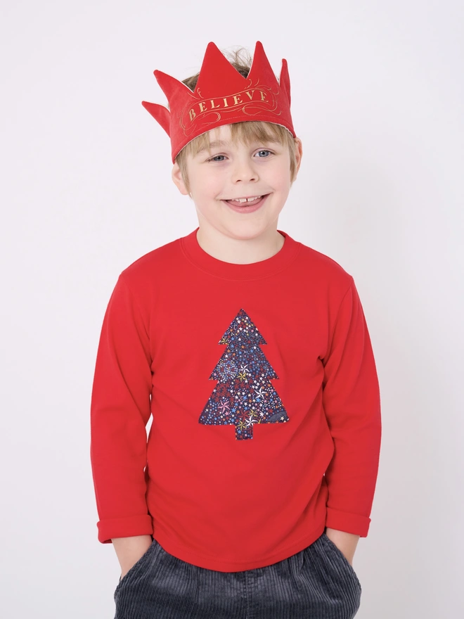 a 5 year old boy wearing a red tee with a christmas tree cut from starry liberty print sewn onto the front