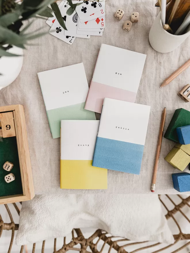 set of four notebooks white at the top with a coloured band at the bottom. one each of pink, green, yellow and blue