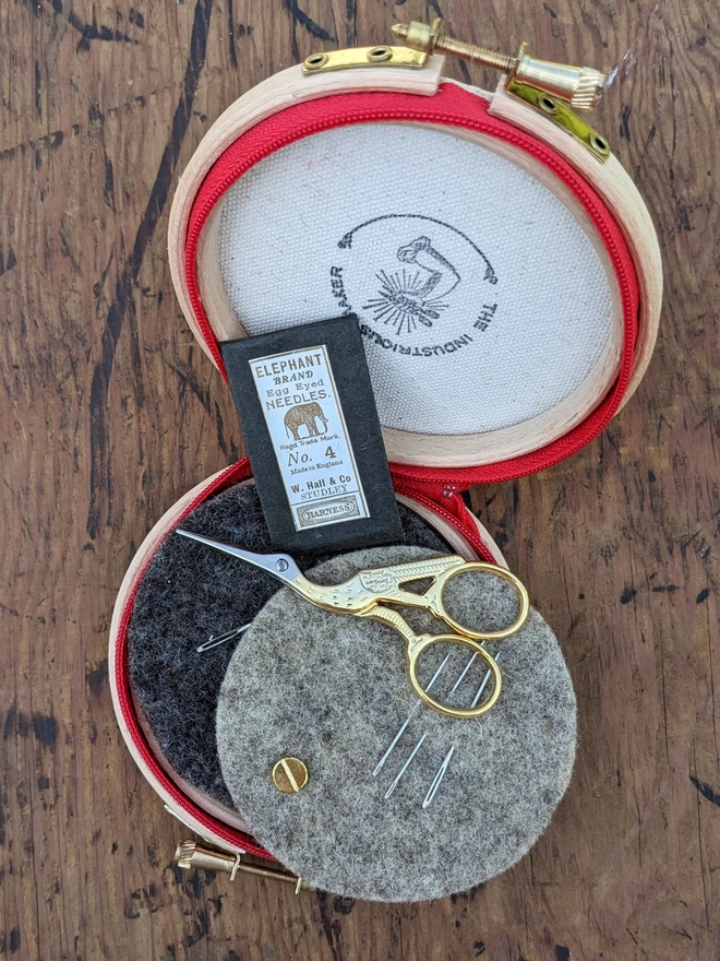 Royal bluTthe needle is mightier' embroidery hoop needle book shown open with inner felt, needles, scissors and a packet of pins
