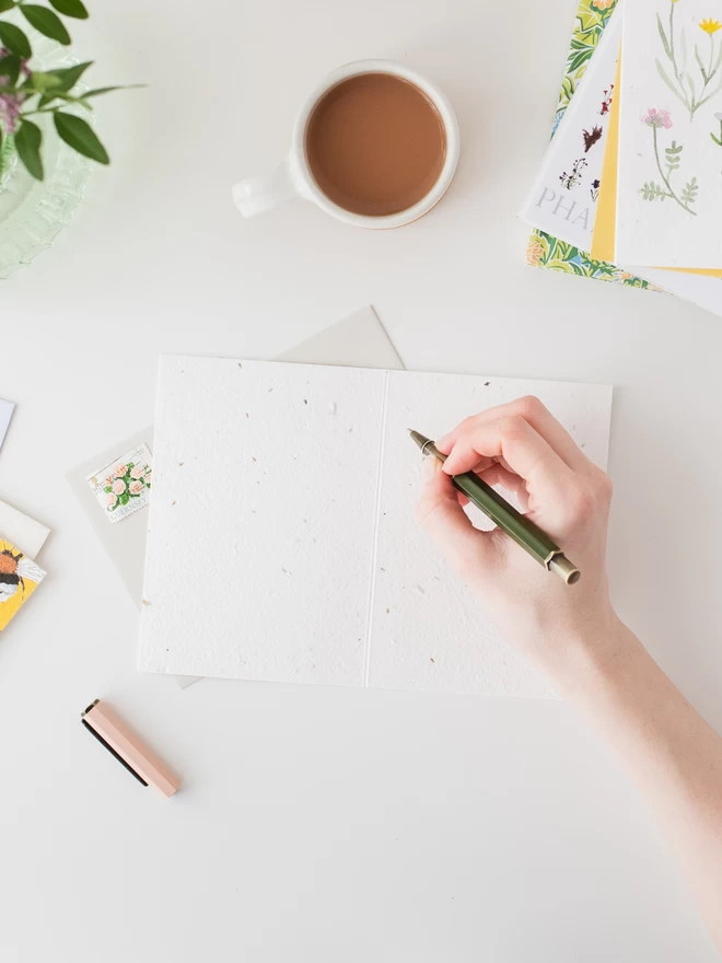 A lady writing in a Ruby & Bo plantable card