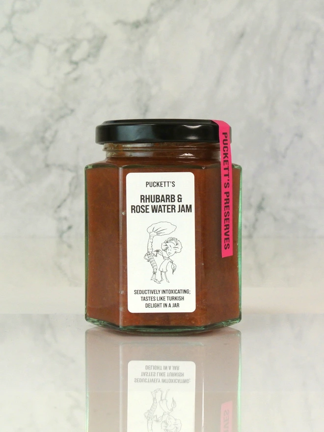rhubarb and rose water jam. a jar of rhubarb jam photographed against a marble background.