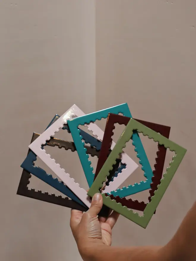 person holding various empty stamp shaped frame mounts