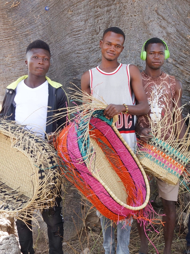 Ghanaian weavers holding part-woven baskets
