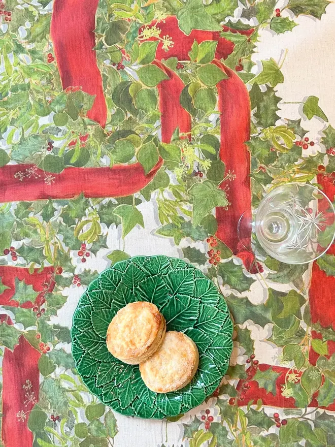 christmas garland lattice tablecloth. a tablecloth printed with holly, ivy and mistletoe on a table.