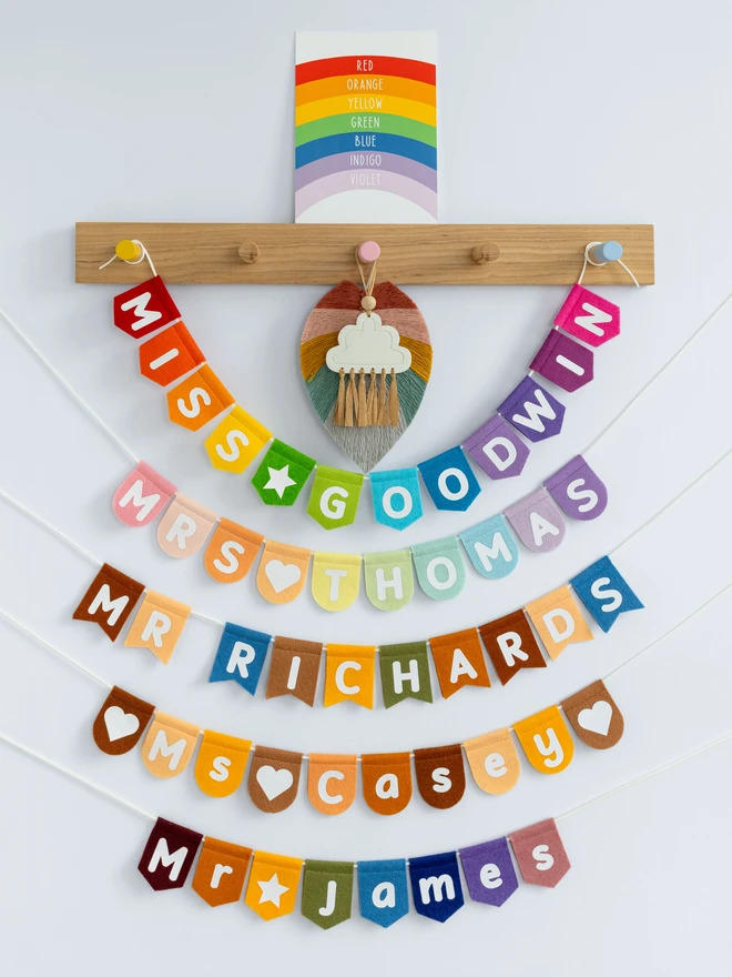 A range of different  coloured bunting with a teachers names on them in white.