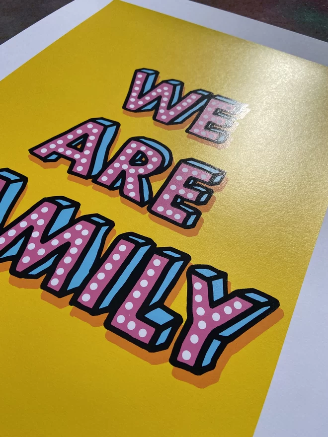 Portrait "We Are Family" Hand Pulled Screen Print with yellow back ground and hand drawn letters that say “we are family” with an extra drop shadow in orange 
