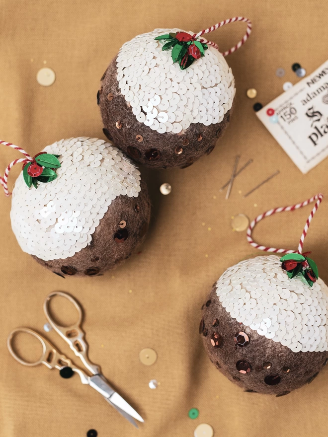 3 Sequinned Christmas Puddings on a golden linen cloth