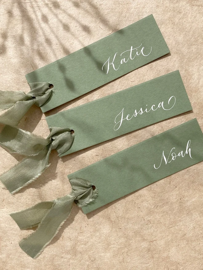 sage green calligraphy wedding place cards. green wedding place cards with silk ribbon and white calligraphy.