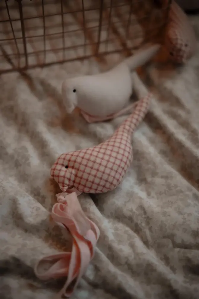 Cotton Bird Garland Decoration, a red and white cotton bird garland sitting on a child's bed accompanied by other bedding accessories. 