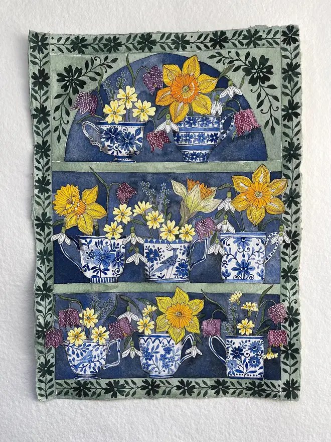 daffodils, snowdrops and spring flowers in delftware teacups displayed in a plant theatre