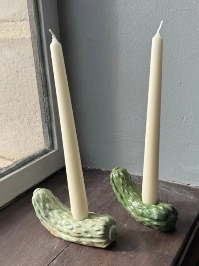 Pickle Candle Holder, a pickle candle holder sitting on a wooden surface with a candle in it. 