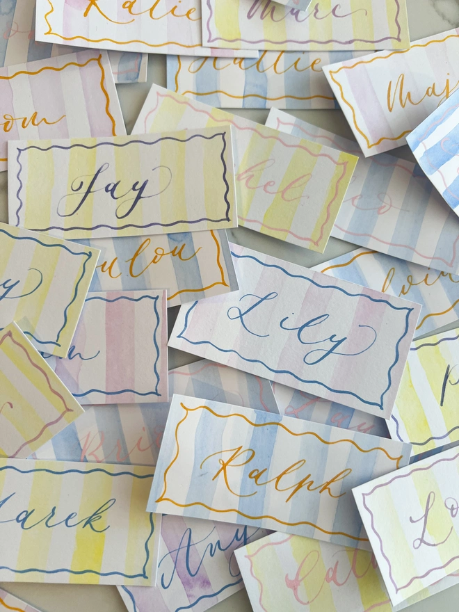 Personalised calligraphy event place cards, striped coloured place cards spread together