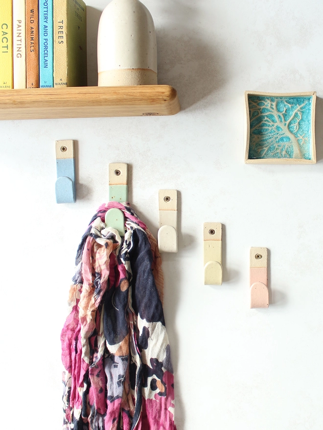 5 pastel hooks on wall surrounded by decor