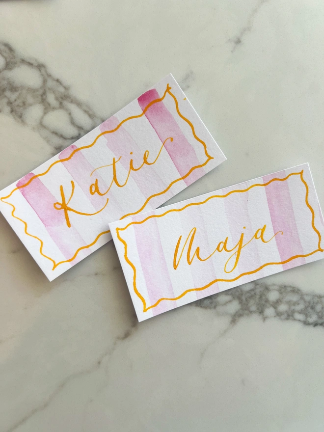 Personalised calligraphy event place cards, pink striped coloured place cards with orange calligraphy name
