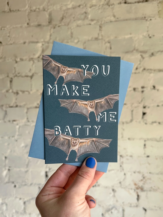 deep blue card featuring a realistic illustration of three bats and the text "You Make Me Batty" with a blue envelope
