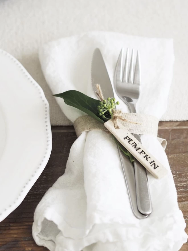 napkin tied with a ceramic tag that reads 'pumpkin'