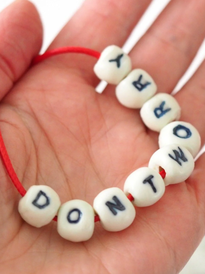 Don’t Worry necklace. A red cord with beads reading ‘DONT WORRY'