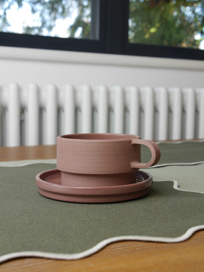 Damson coffee mug and saucer set on a table