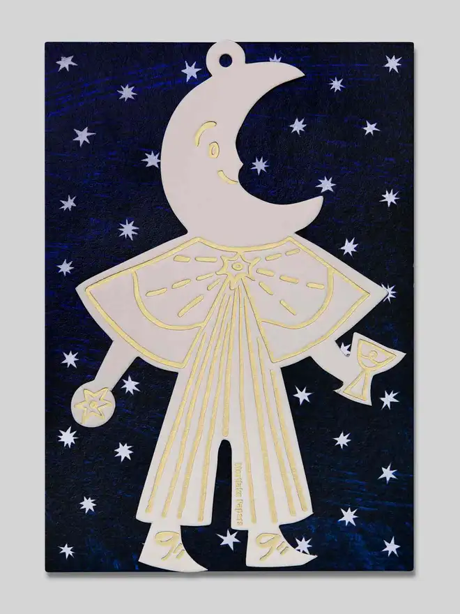 Decorative ornament shaped like a stylized figure with a moon face on starry sky packaging