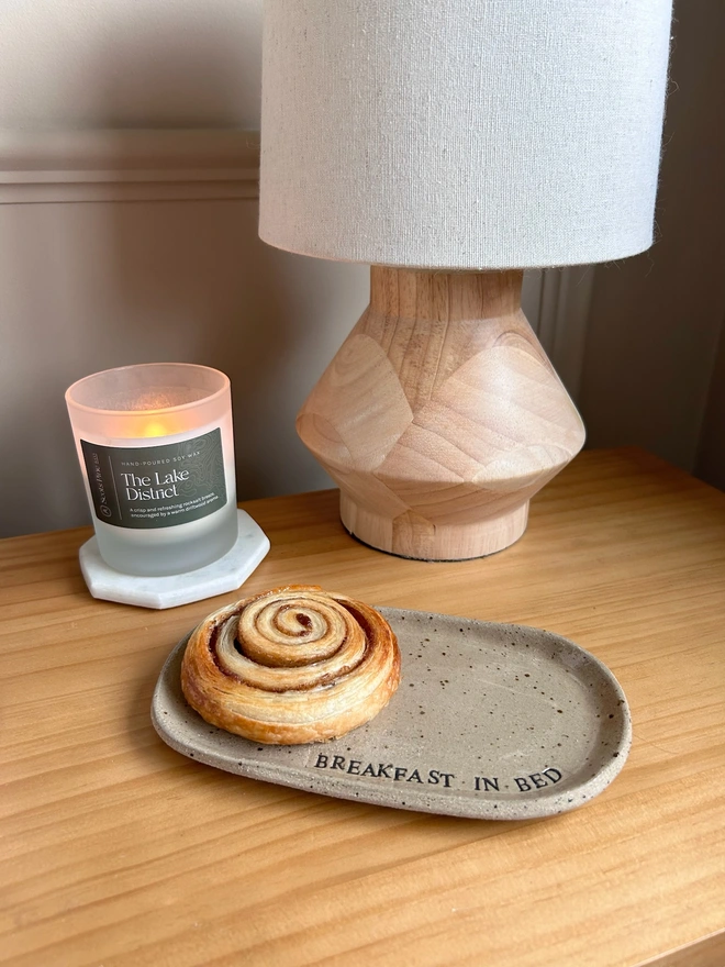cinnamon swirl on an oval pate beside a lamp and candle