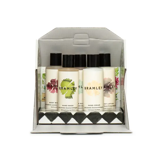 interior of cardboard box in the shape of a greenhouse, with five bottles of body products with white labels and black lids design