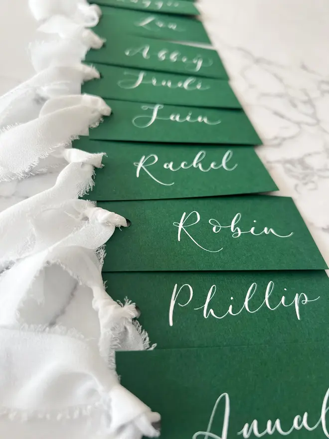 Personalised Calligraphy Wedding Green Place Cards, grouped together with white ribbon. 