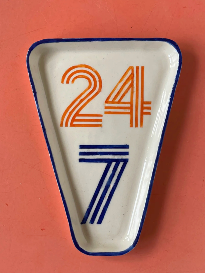 24/7 Dish. A triangular dish with 24/7 printed on.