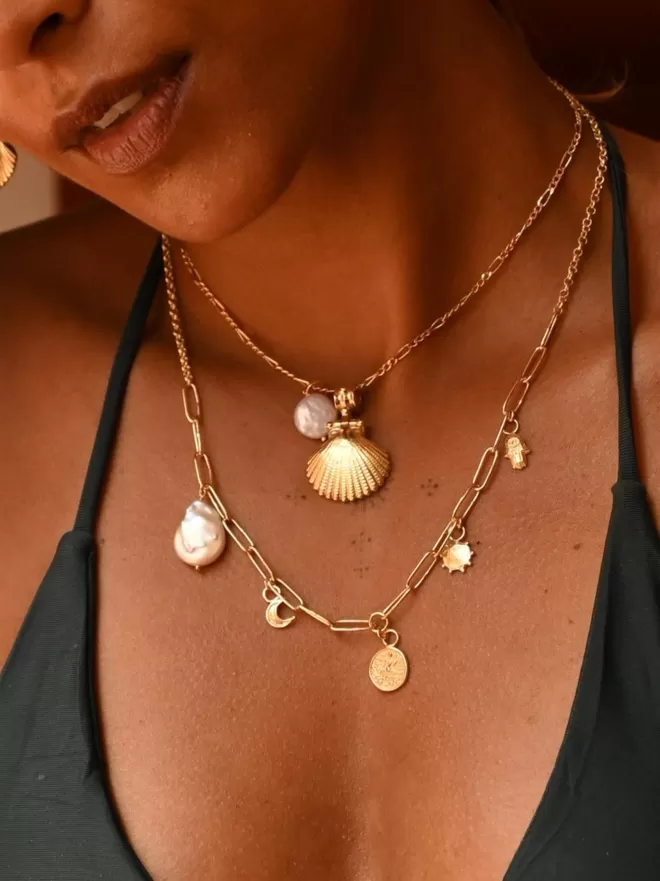 Model wearing gold vermeil shell pendant with charm necklace with baroque pearl