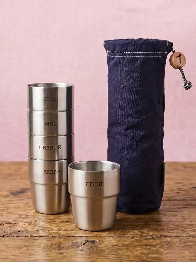 A set of personalised steel cups next to a navy blue storage bag