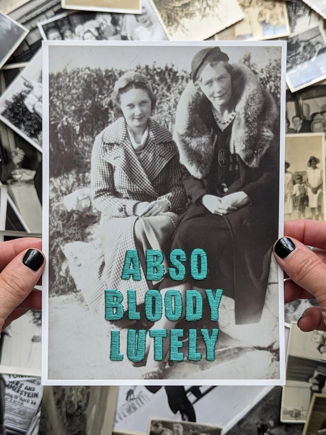  B&W photo of 2 women with Abso-bloody-lutely in teal embroidered across, print version