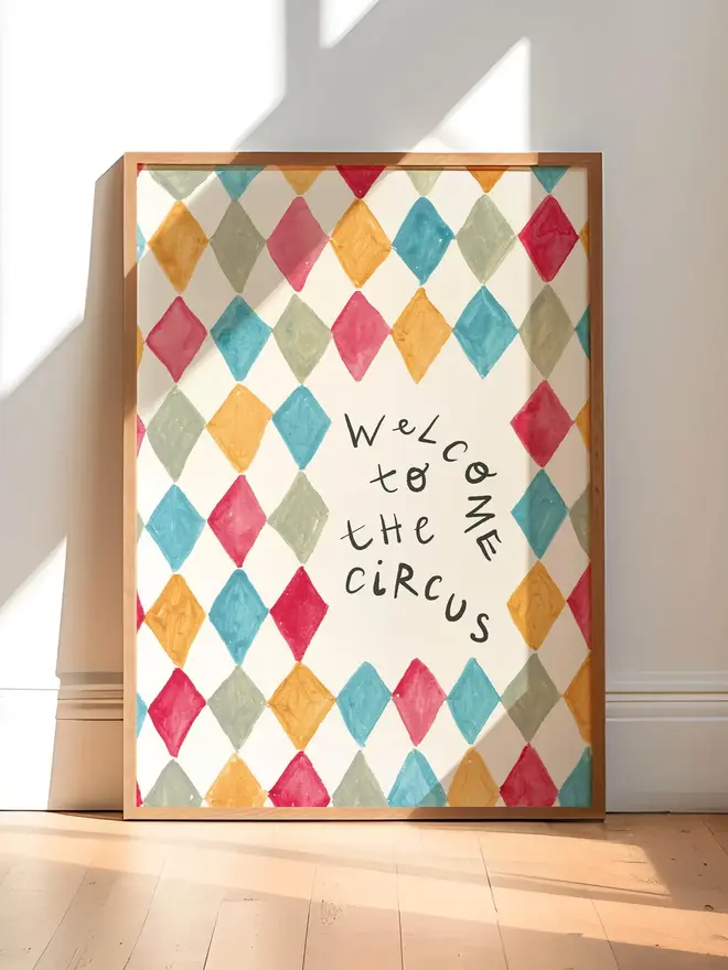 'welcome to the circus' art print. a print with a colourful diamond pattern background and a slogan in black letters. 