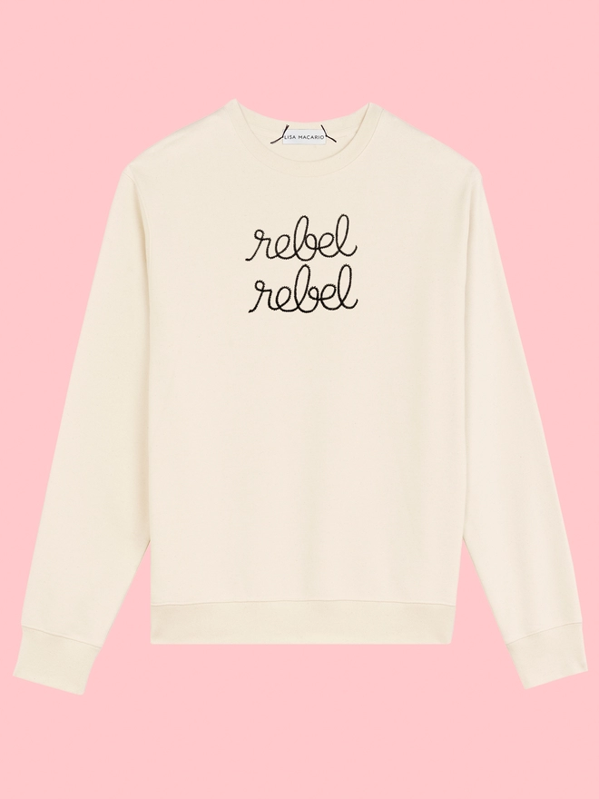 A natural sweatshirt embroidered with rebel rebel on a pink background
