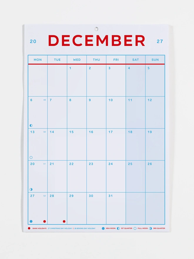 Monthly view calendar in red and blue on white recycled paper, photo shows the month of December