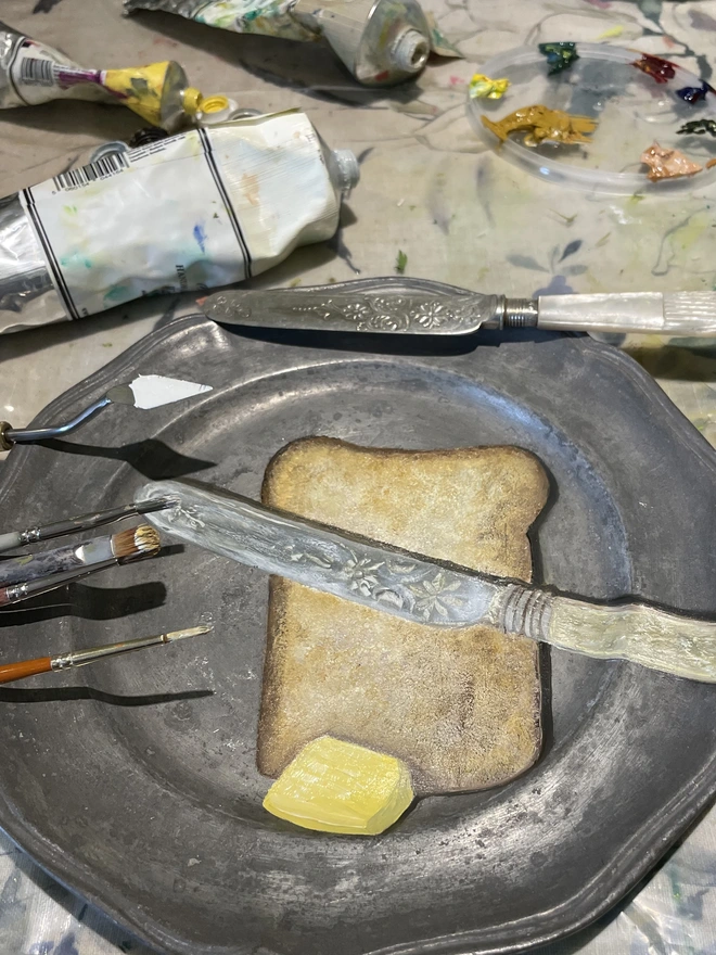 painting in the studio of bread and butter on pewter plate 