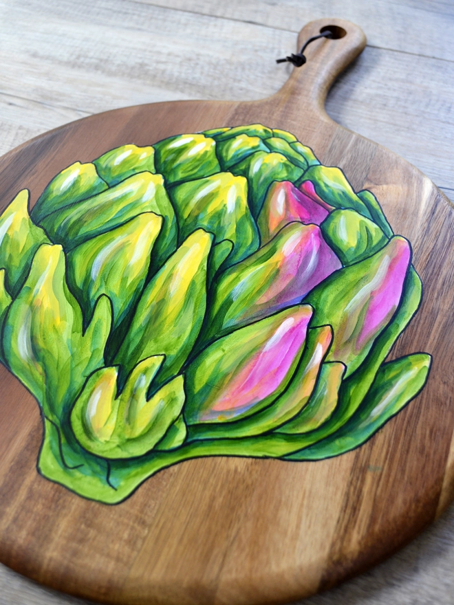 Closeup of wooden serving board with handpainted artichoke design