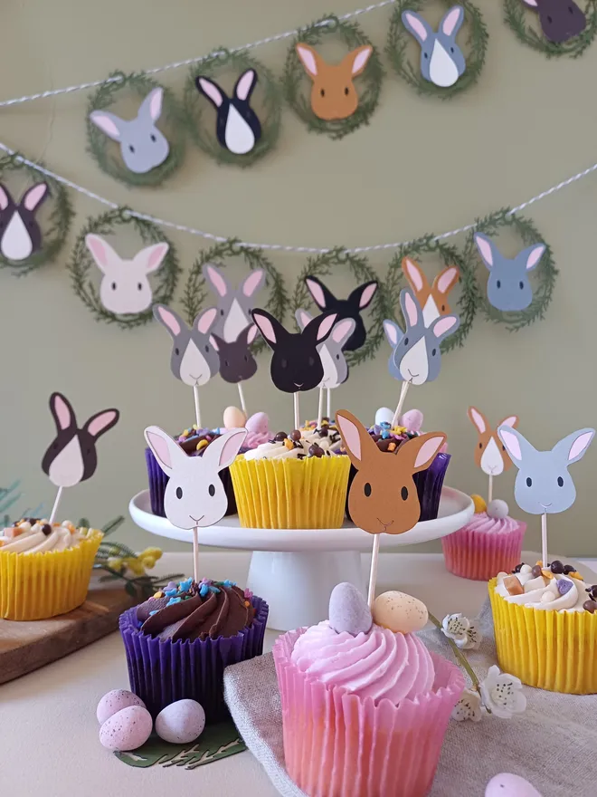 Easter Bunny Cupcake Toppers displayed in lifestlye scene with Easter bunny garland on wall in background